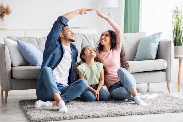 Familie, welche ein Haus imitiert um zu zeigen, dass sie perfekt abgesichert sind.